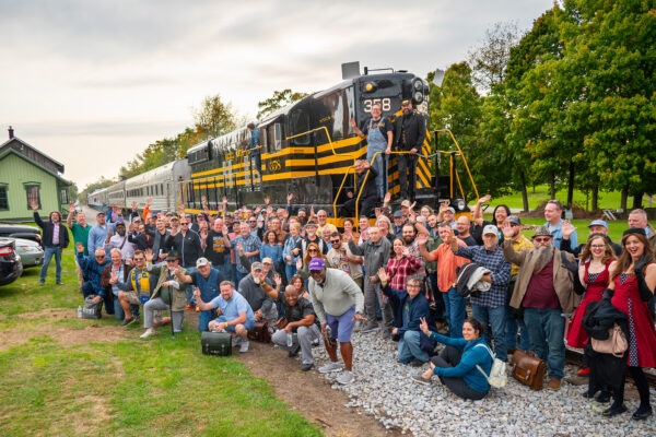 Nickel Plate SD9 cigar train 12
Back in the starting point of Pleasant Lake, Indiana, passen gers and volunteers pose with the  “Rocky Patel Rolling Smoke Cigar Train”. 
Rocky Patel, owner of Rocky Patel Premium Cigars, . is seated on the platform below engineer Will Carney and conductor Chris Homco.
Steve Smedley